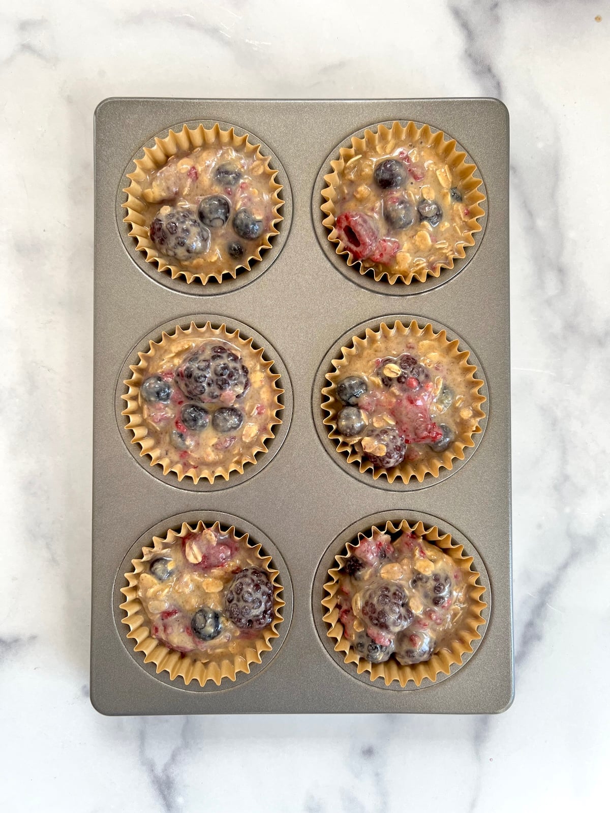 Mixed berry muffins in muffin tin ready to bake.