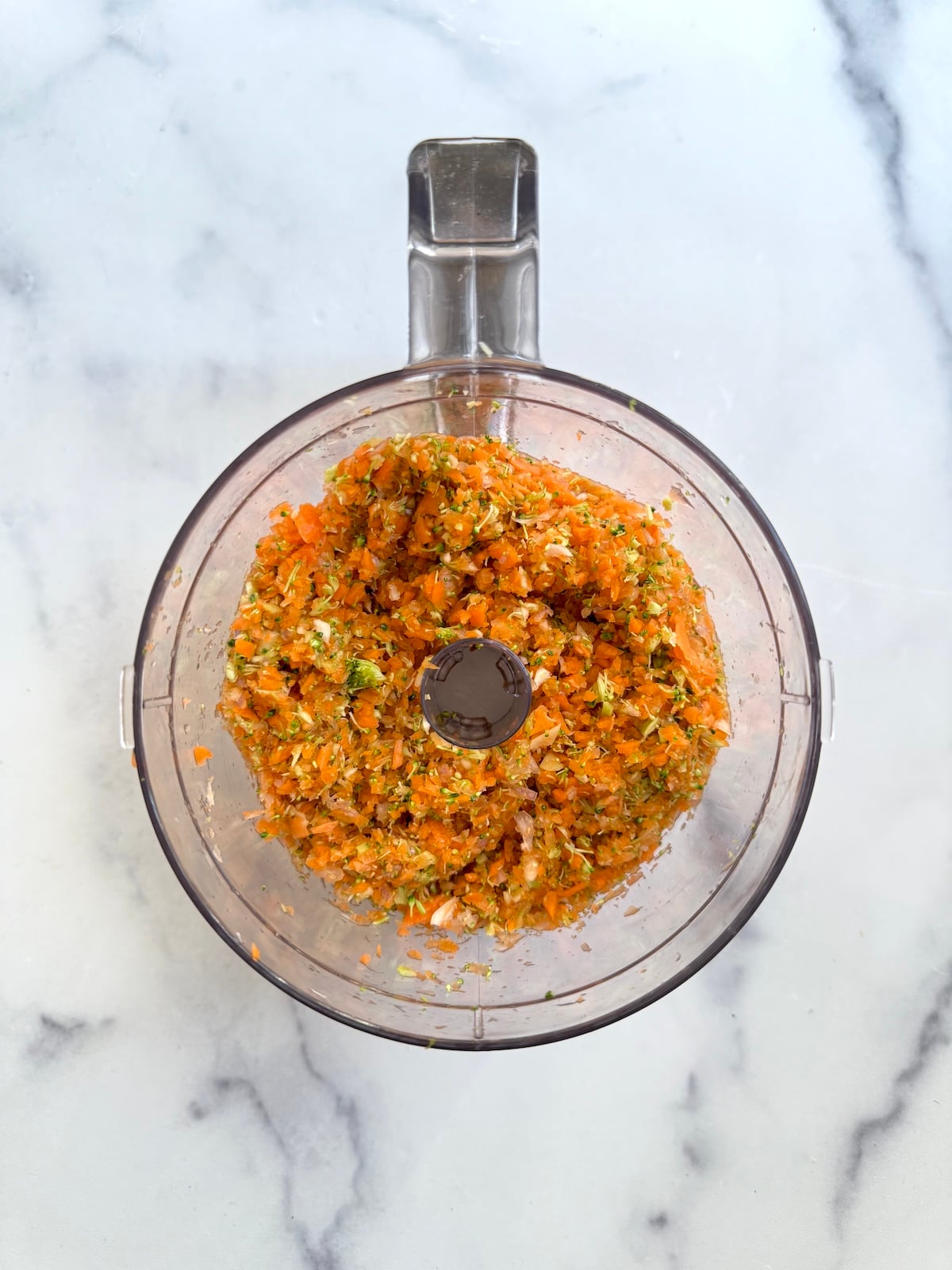 Chopped carrots and broccoli in a food processor.