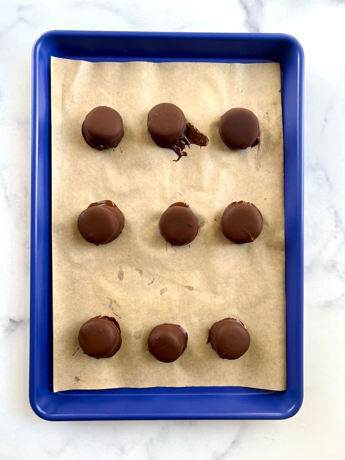 Frozen chocolate peanut butter banana bites on a sheet tray.