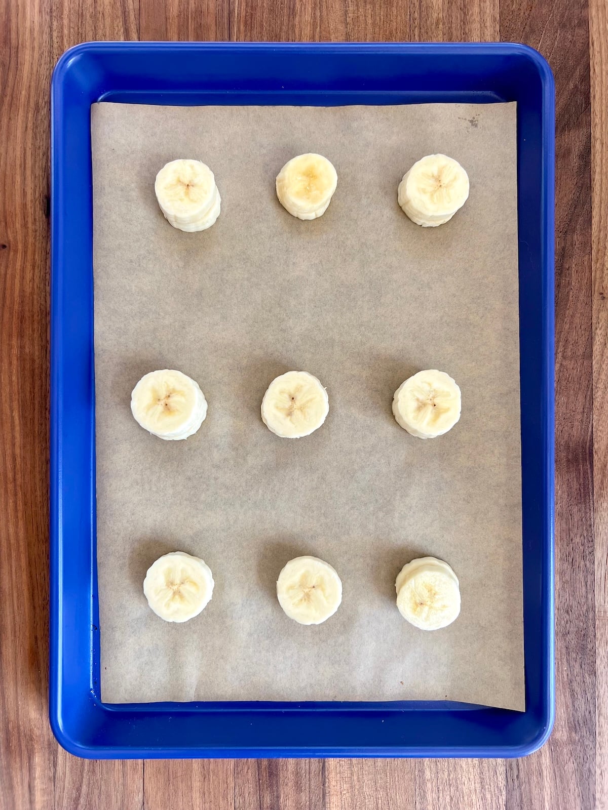 Frozen banana slices with peanut butter on a sheet tray.