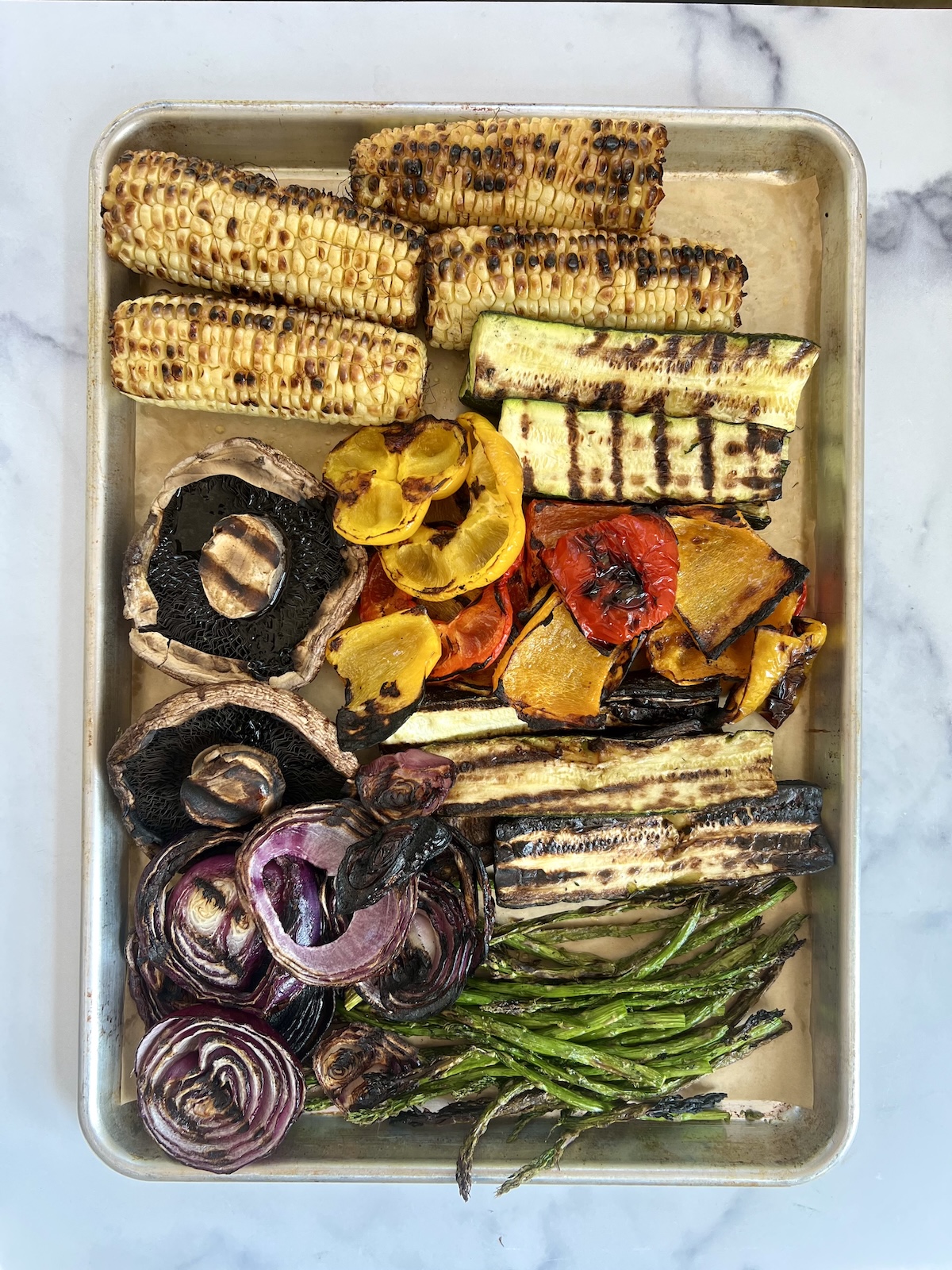 Grilled vegetables on a sheet tray.