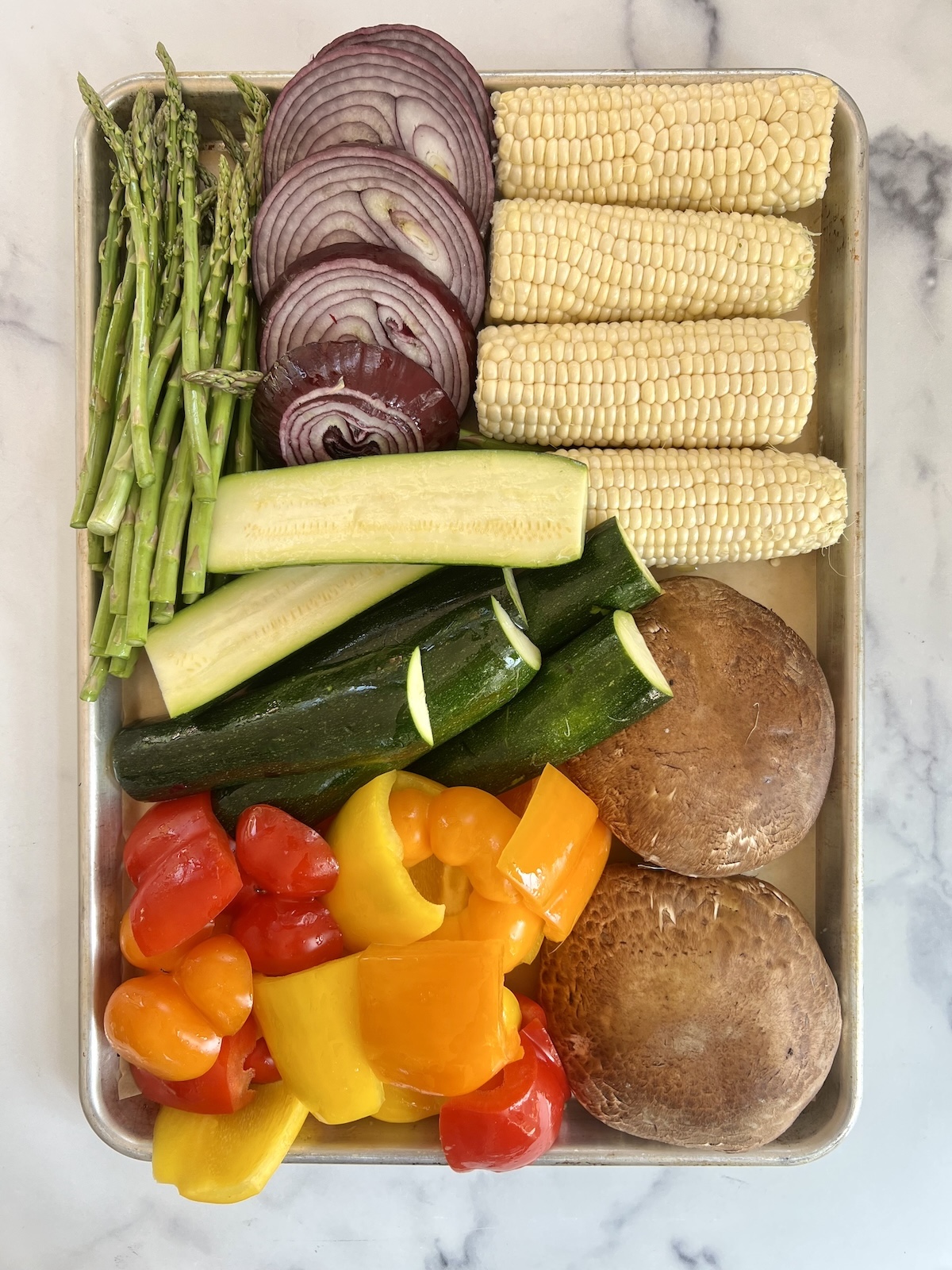 Chopped vegetables on a sheet tray ready to grill.