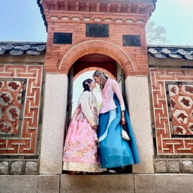 Mother and daughter dressed in traditional hanbok dresses in a doorway.