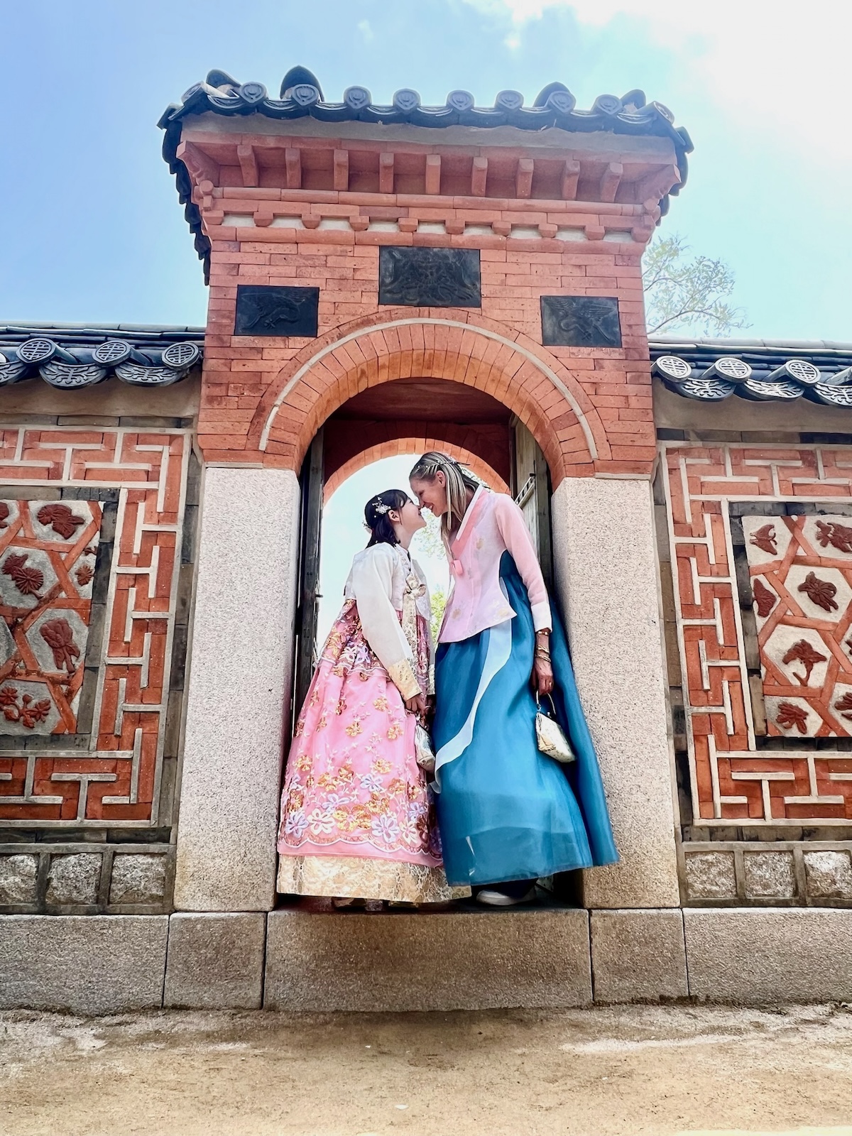Mother and daughter dressed in traditional hanbok dresses in a doorway.