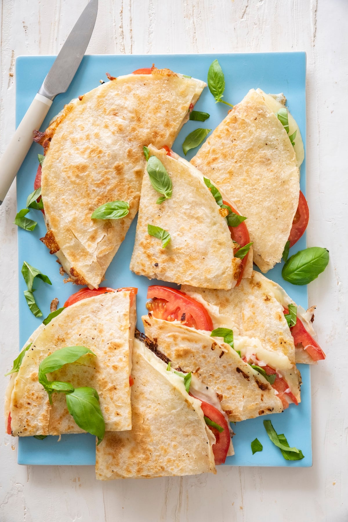 Caprese quesadillas on blue cutting board.