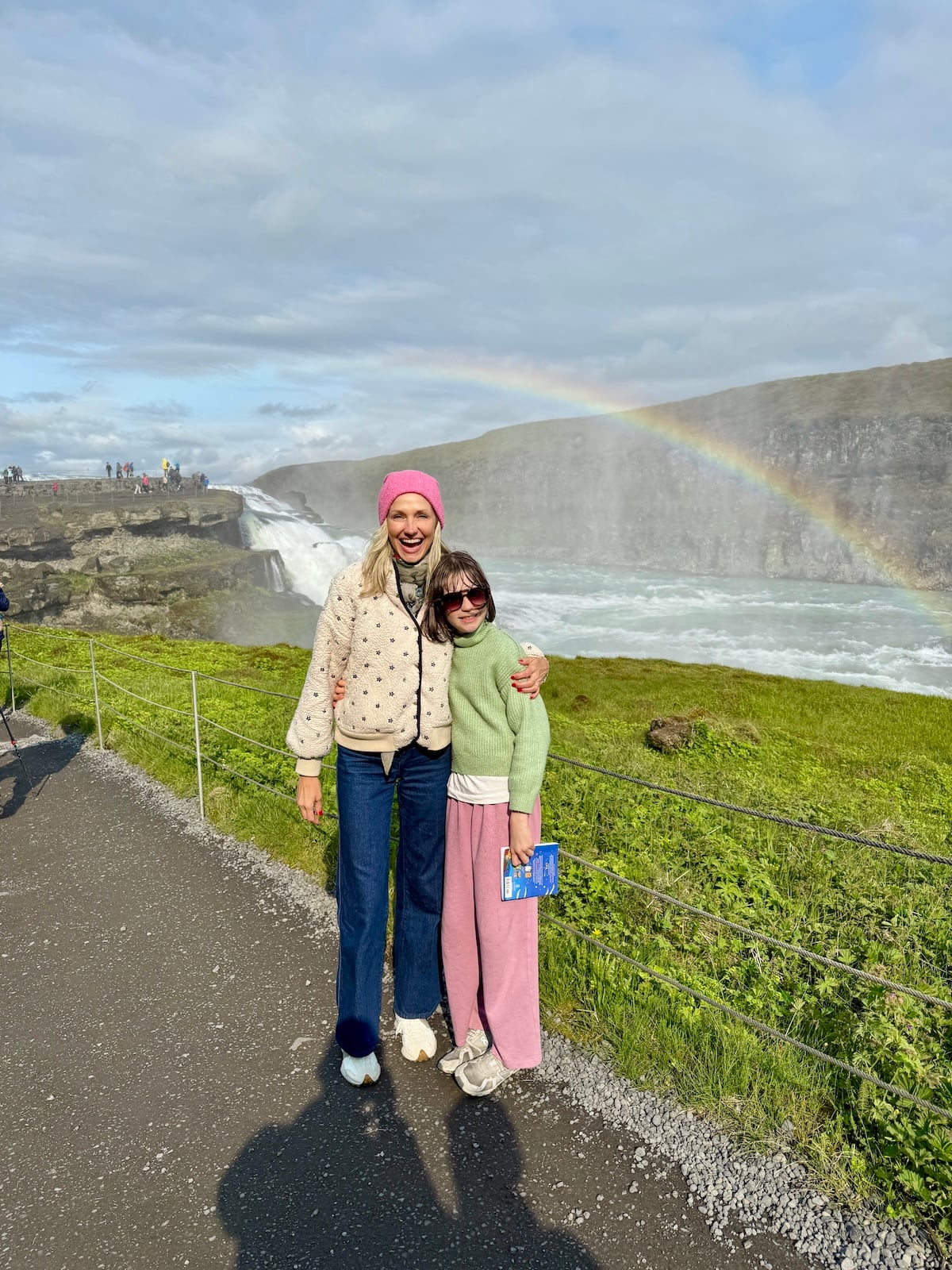 Girl and mother stand in front of a rainbow.