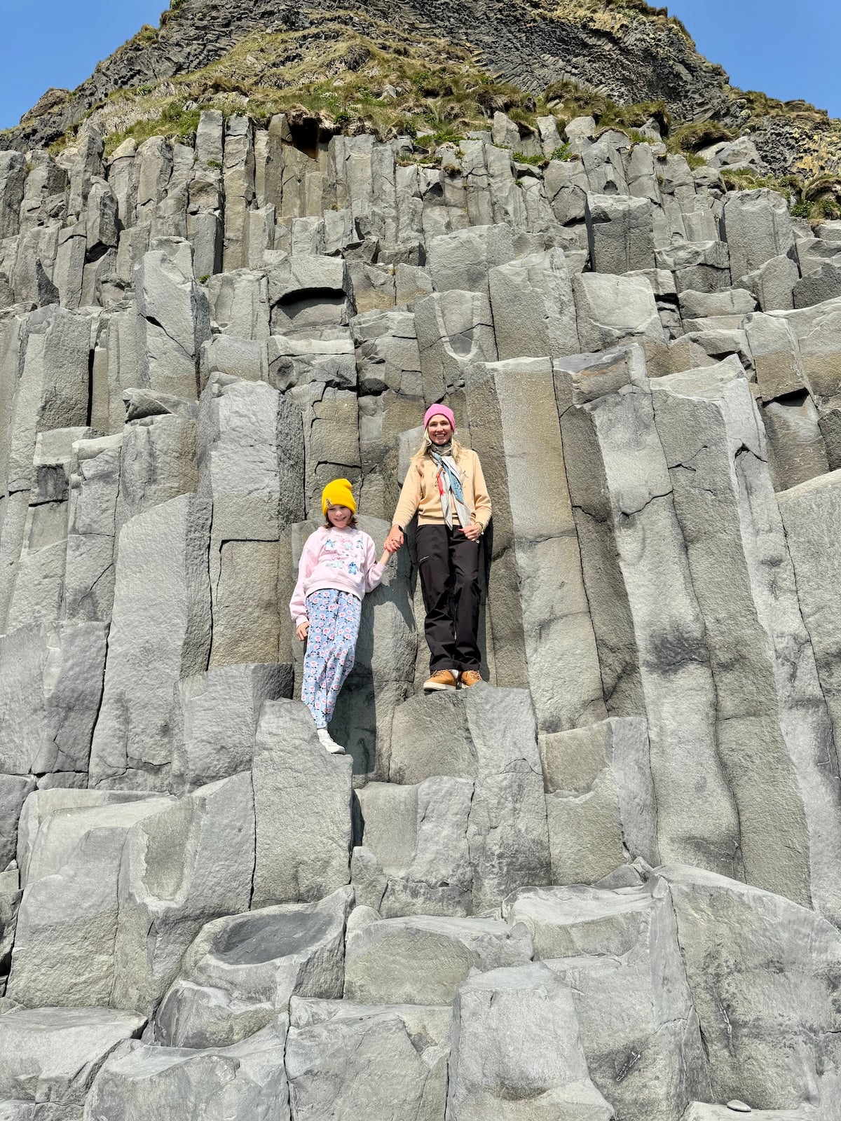 Mother and daughter in front of rock wall.
