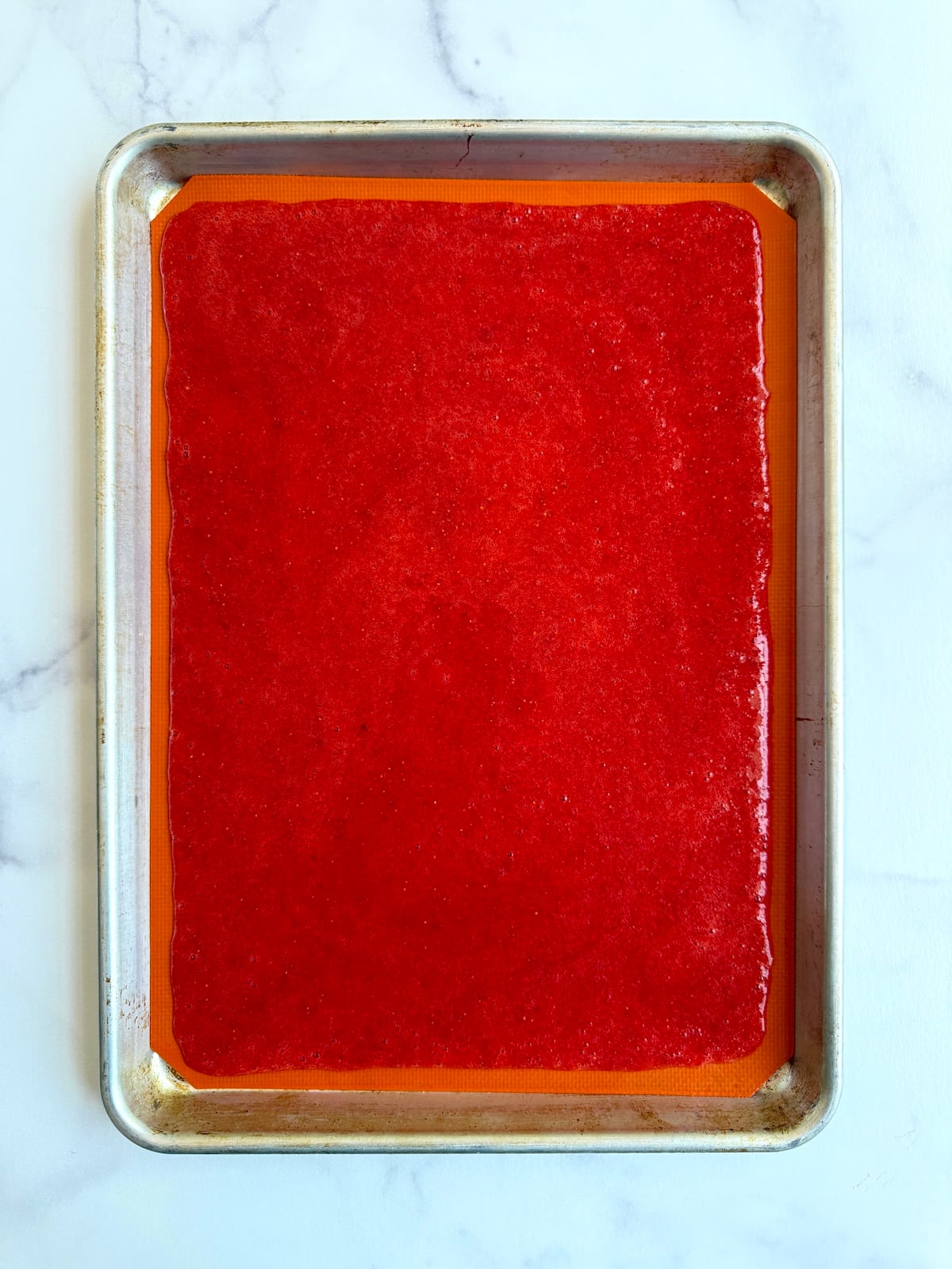 Strawberry puree spread onto a baking sheet.
