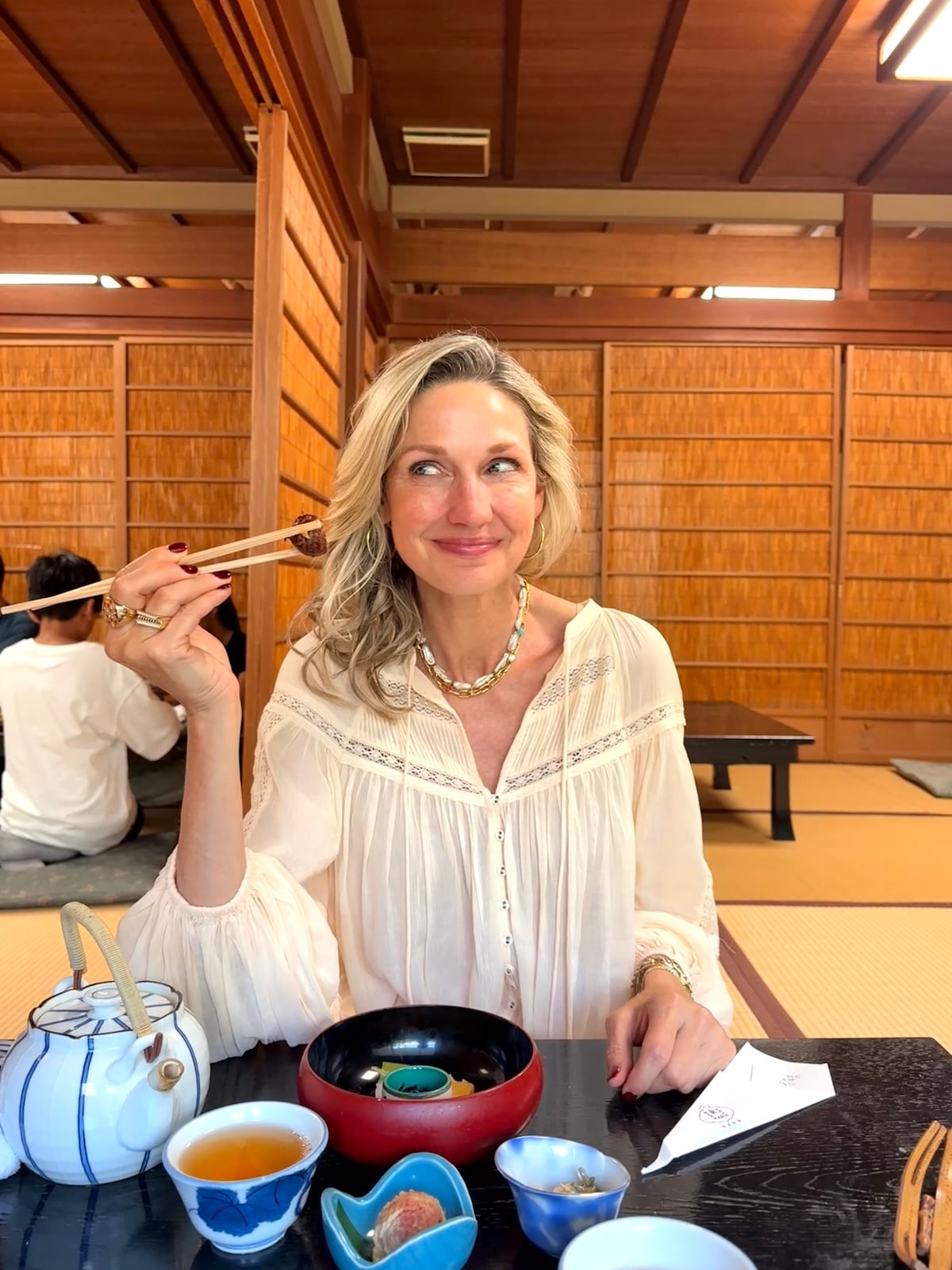 Woman posing with food between chopsticks.