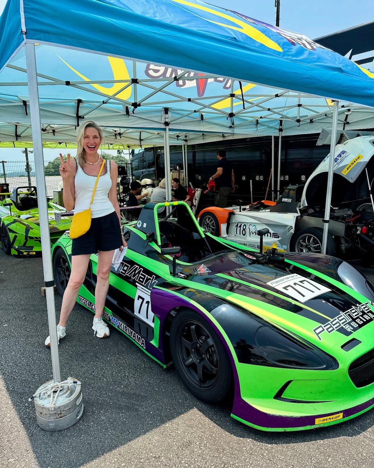 Woman posing with green racecar.