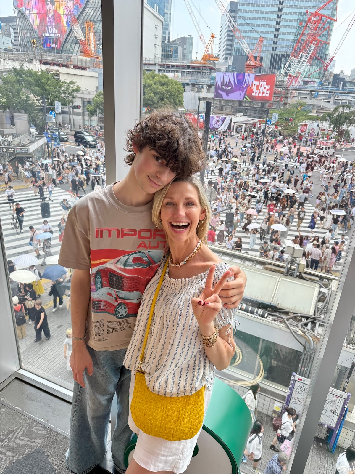 Mother and son posing in front of Shibuya scramble crossing in Tokyo.
