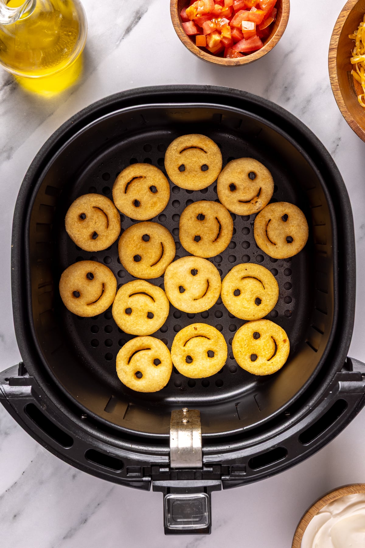 Smile shaped french fries in air fryer basket.