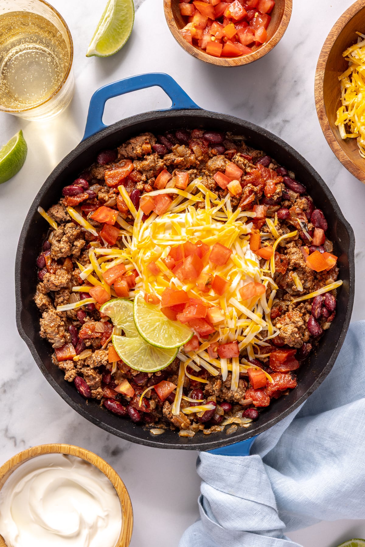 Beef chili with toppings in a cast iron skillet.