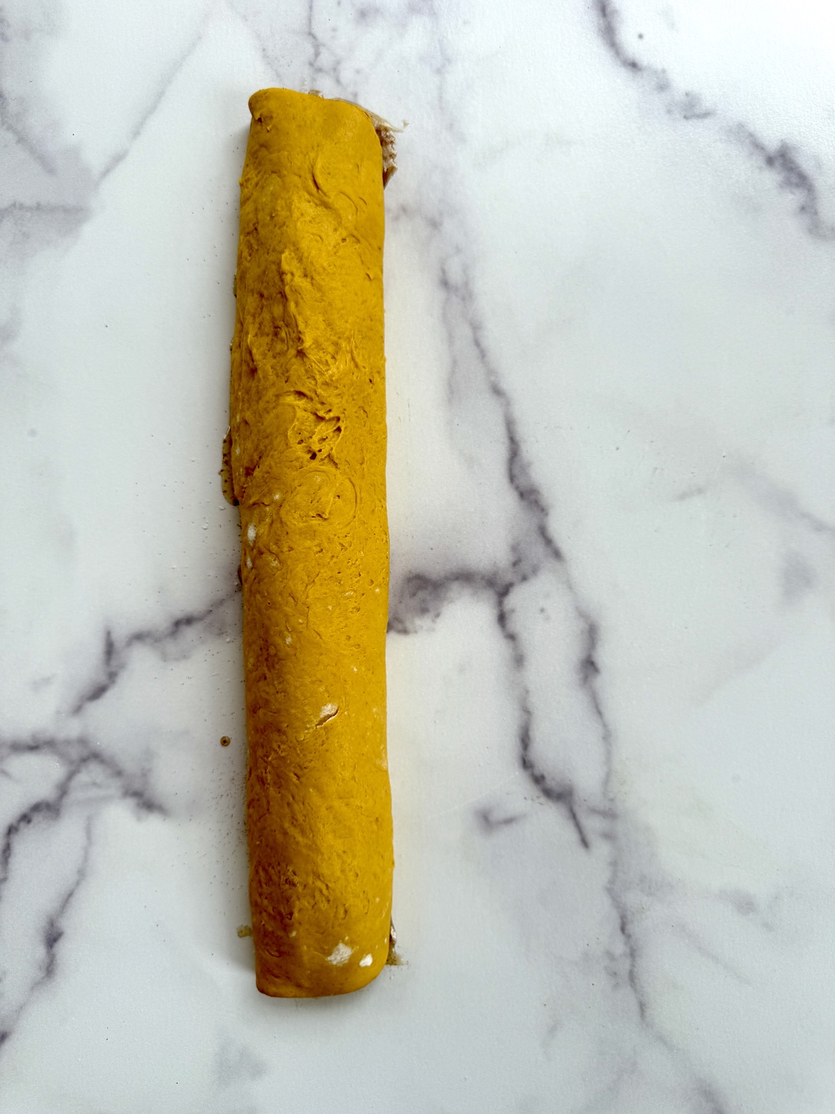 Rolled up cinnamon roll dough before being cut into pieces.