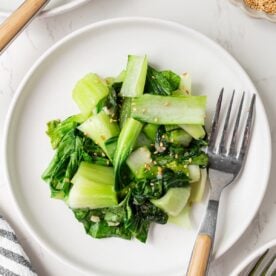 Sauteed baby bok choy on a plate with a fork.