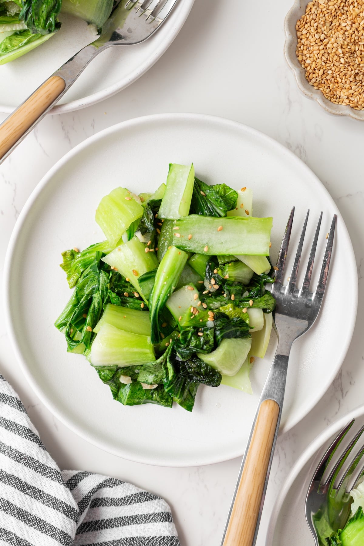 Sauteed baby bok choy on a plate with a fork.