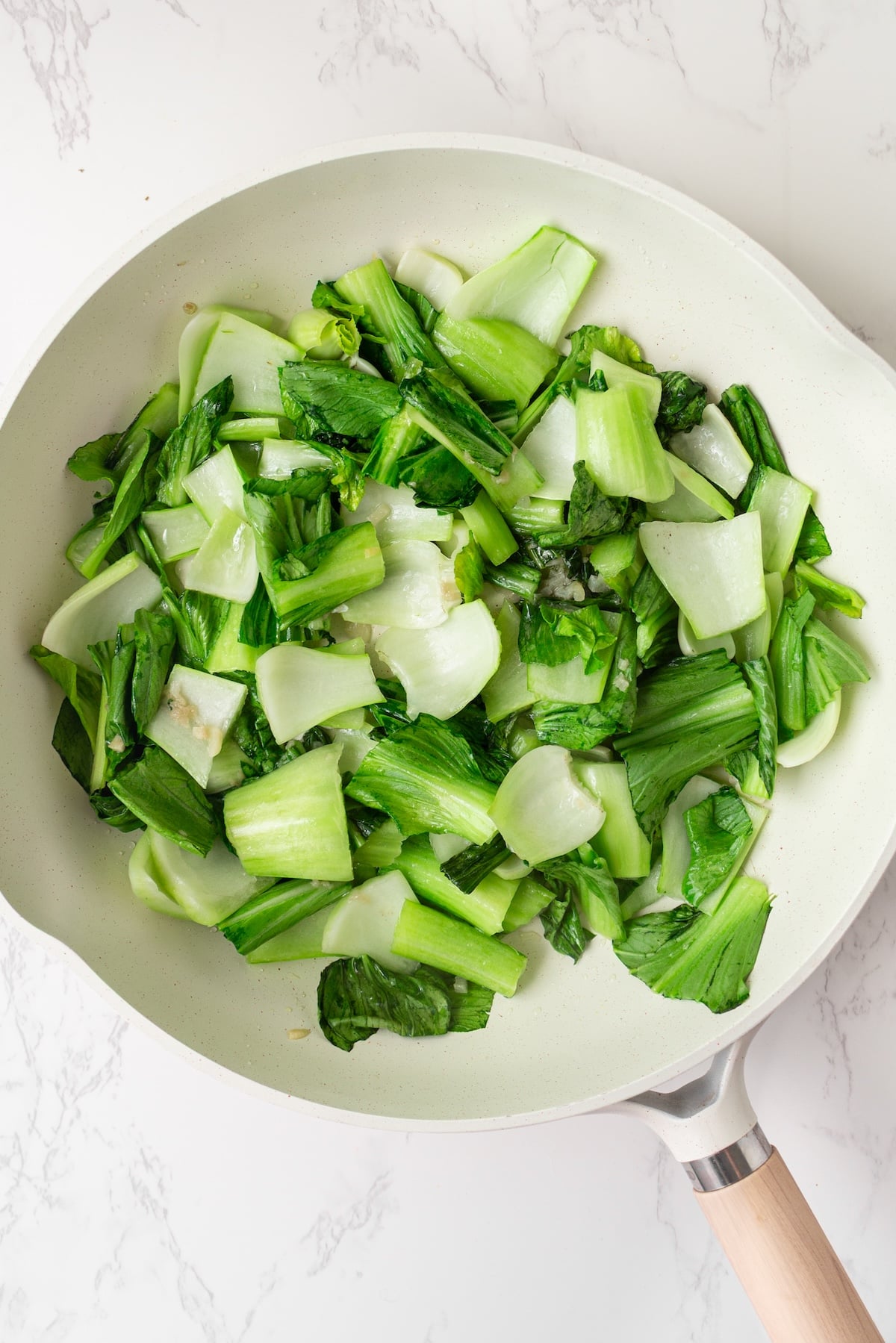 Sauteed baby bok choy in a pan.