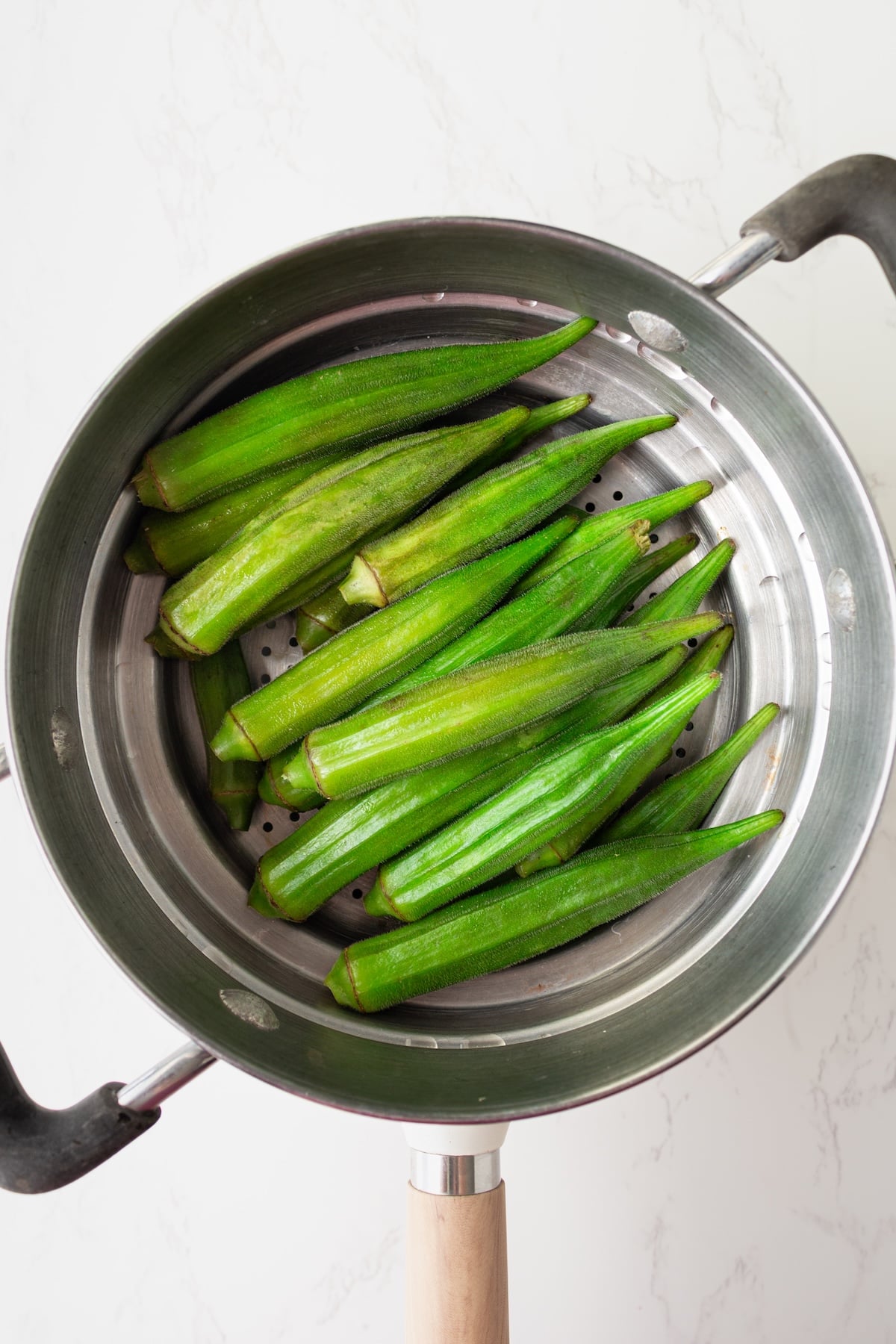 Okra pods in steamer basket.