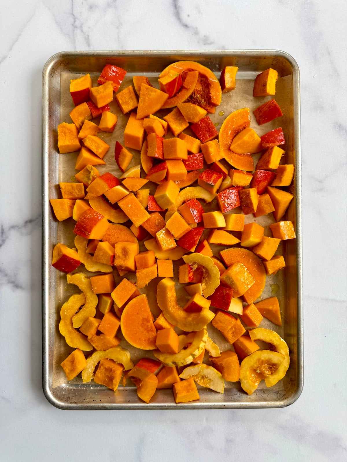 Several varieties of squash on a baking tray.
