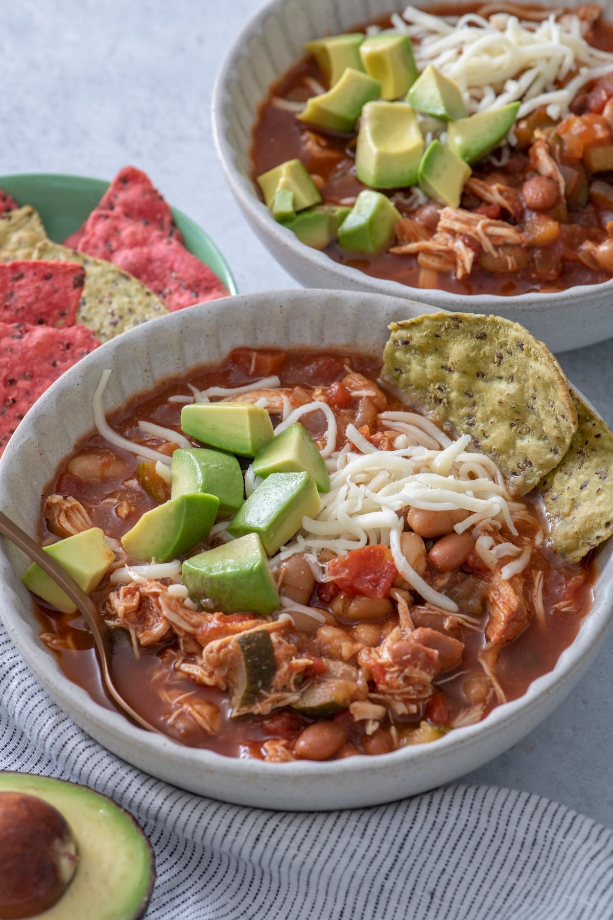 Slow cooker chicken chili in a bowl topped with avocado chunks.
