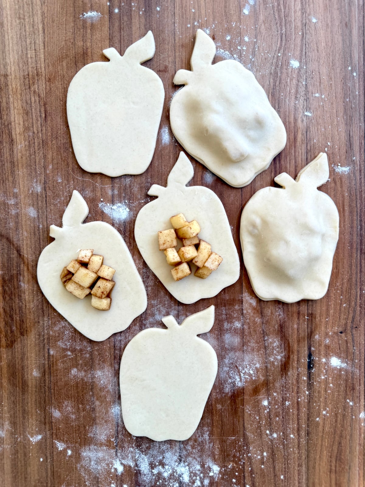 Apple pie turnovers on a wooden surface.