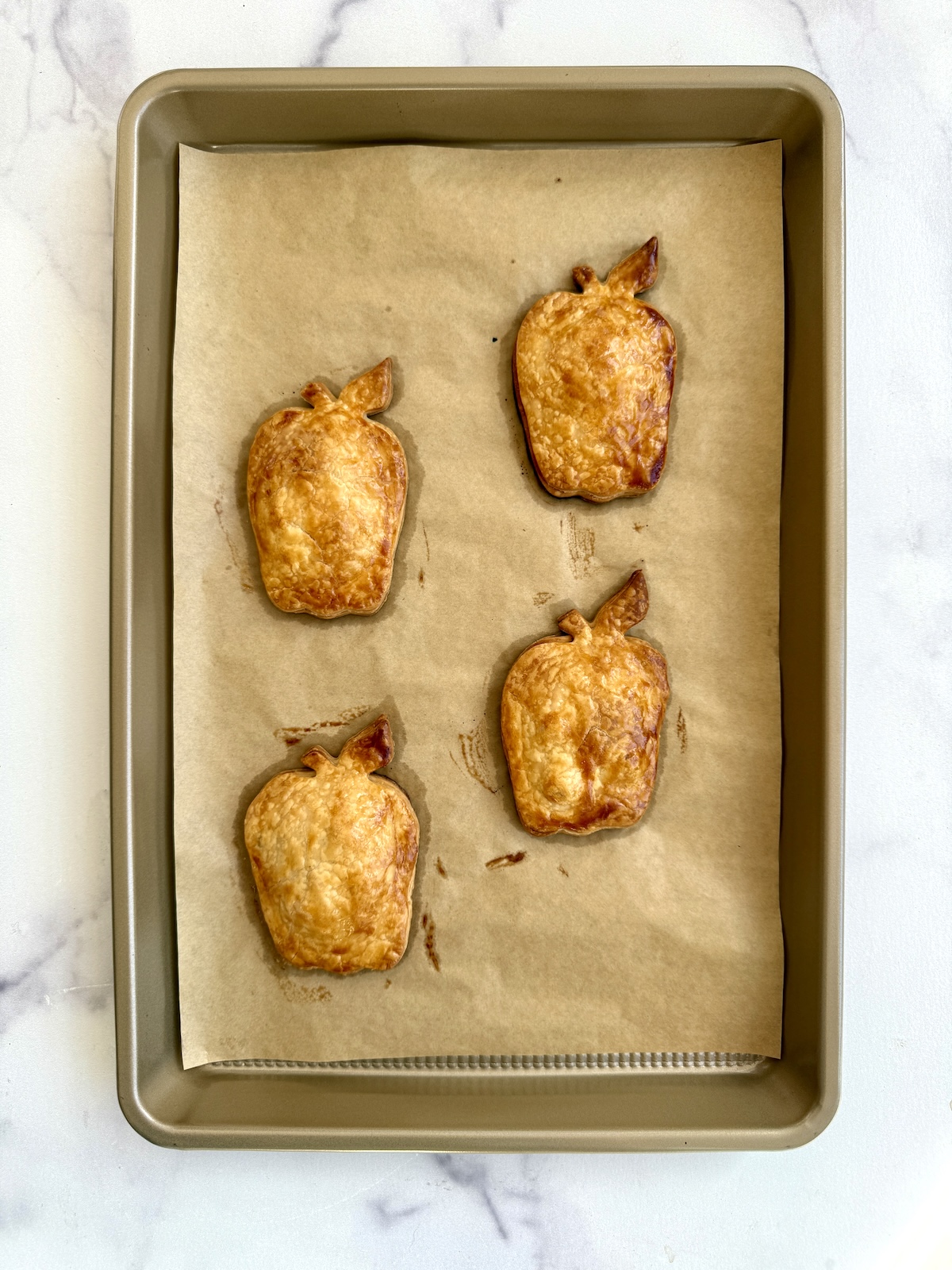 Baked apple pie turnovers on a baking sheet.