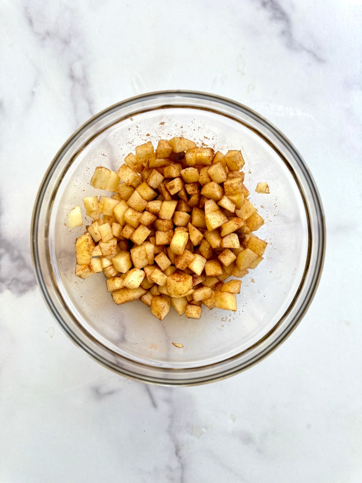 Diced apples, brown sugar and cinnamon combined in a mixing bowl.
