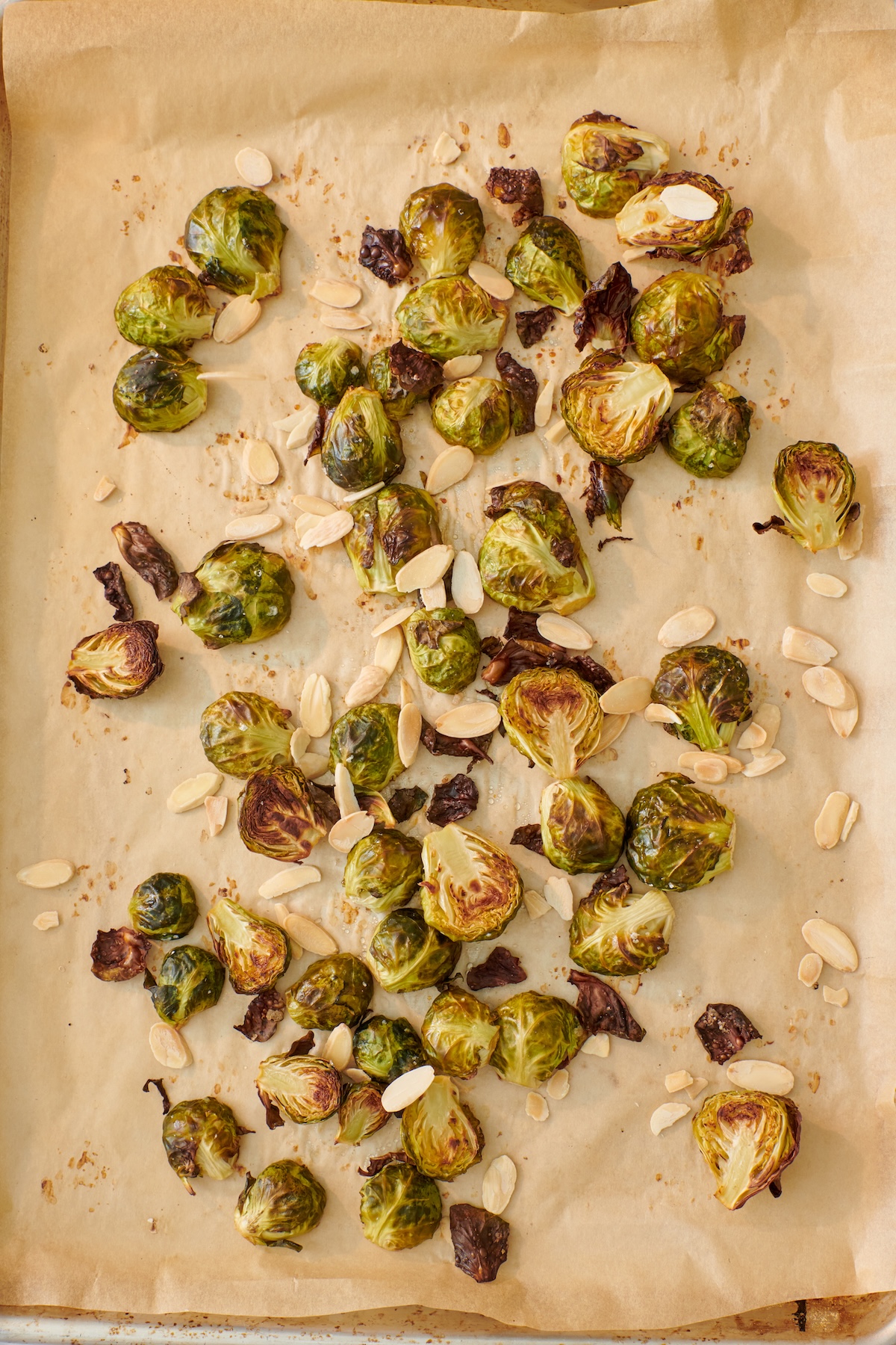 Roasted Brussels sprouts with sliced almonds on a sheet tray.