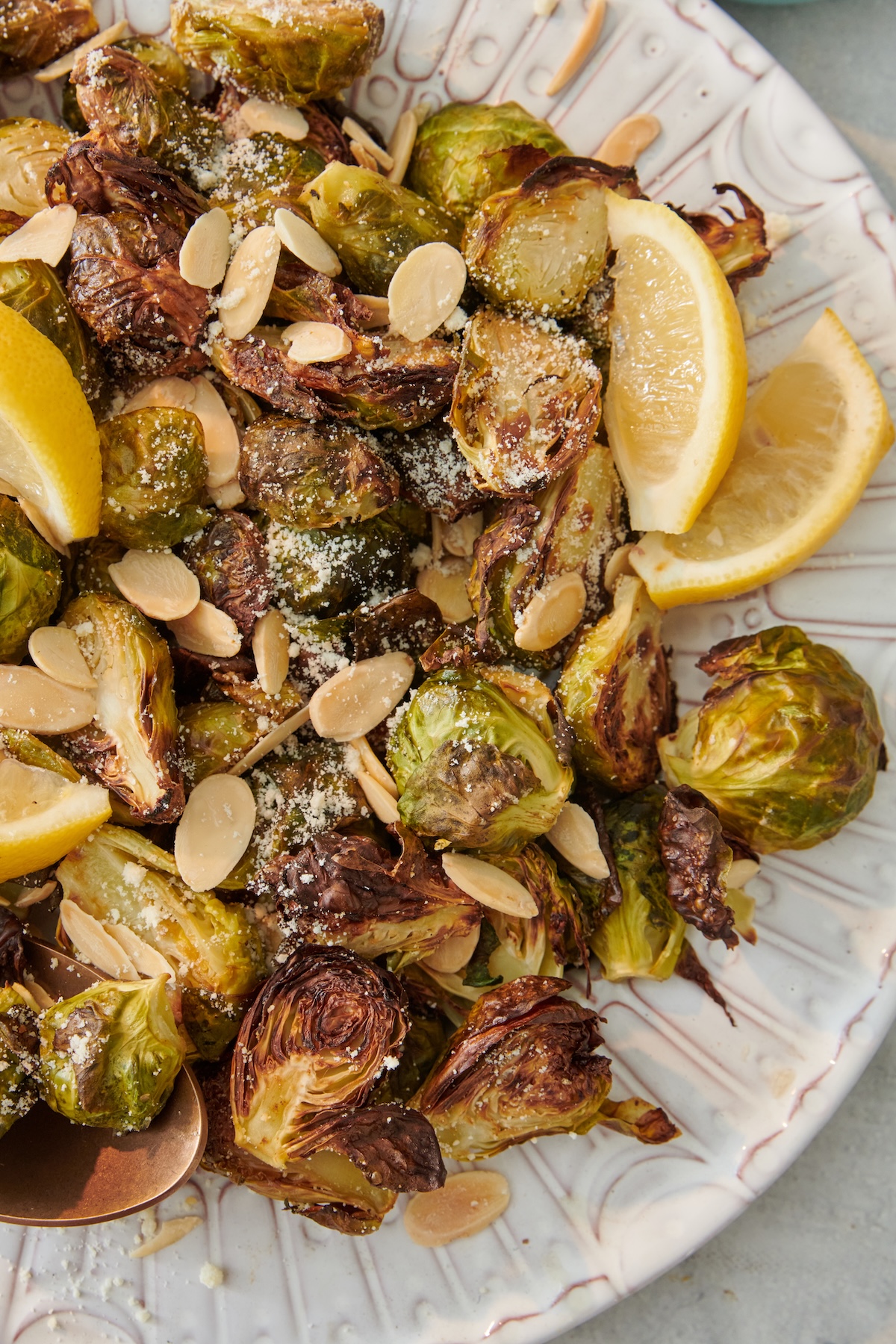 Roasted Brussels sprouts with sliced almonds, Parmesan cheese and lemon on a plate.