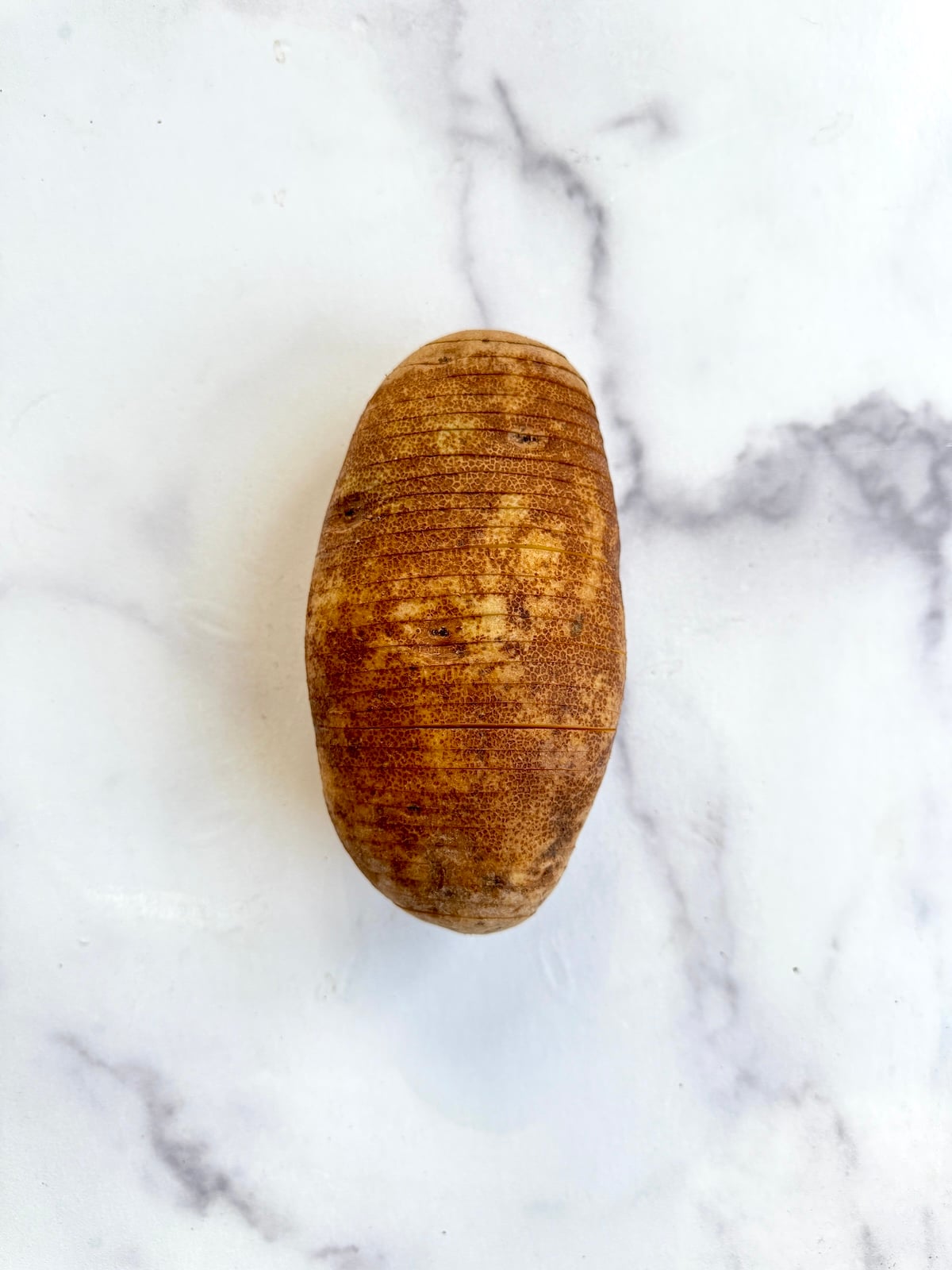 A sliced hasselback potato before baking.