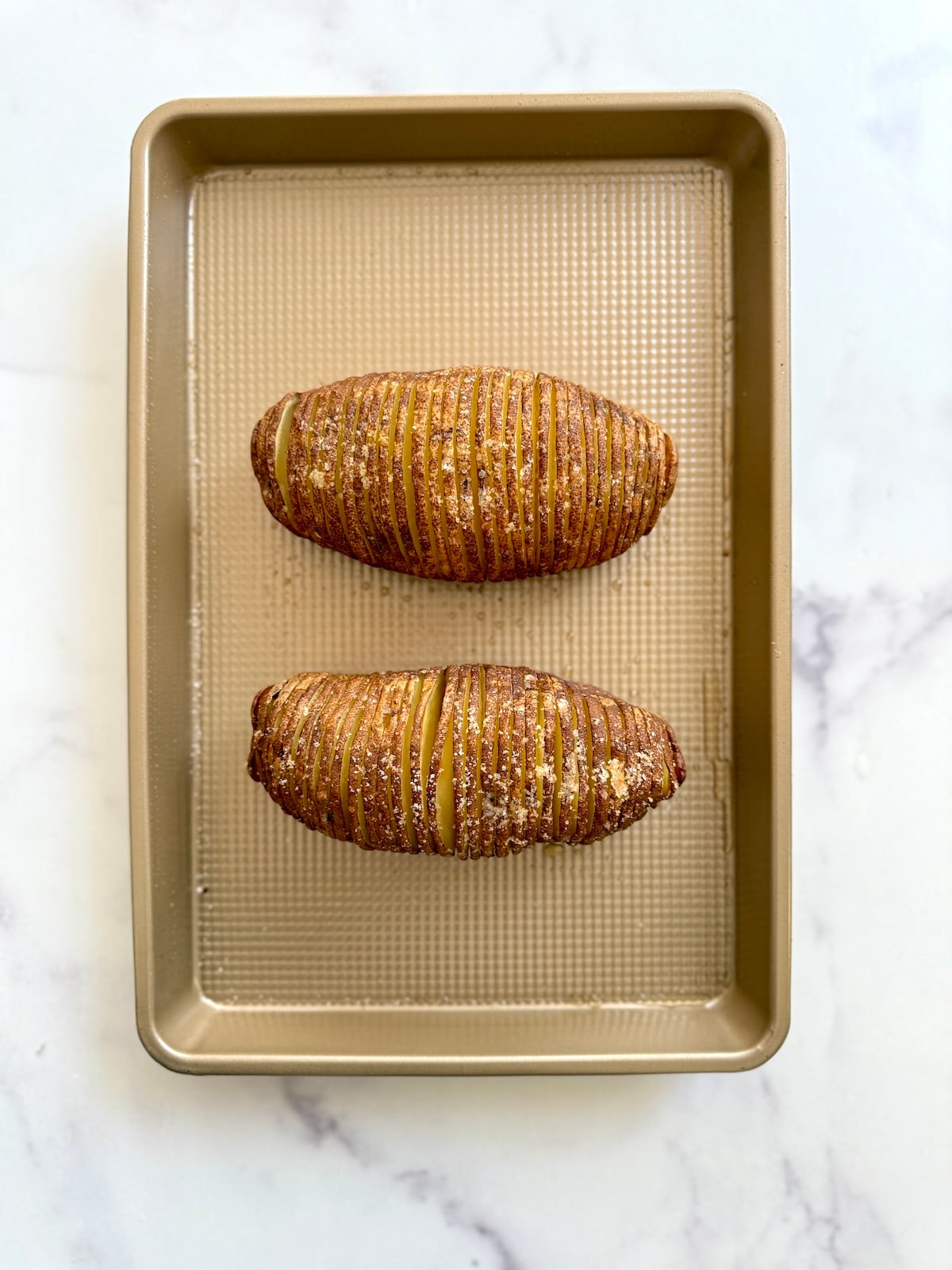 Baked hasselback potatoes on a baking sheet.