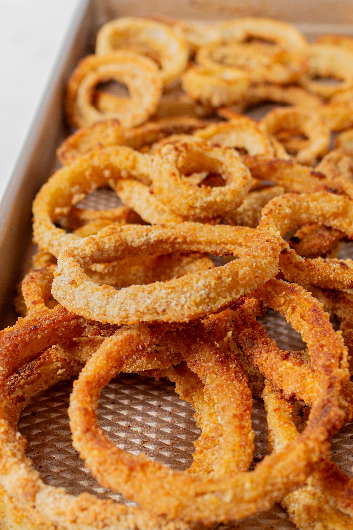 Crispy onion rings on a sheet tray.