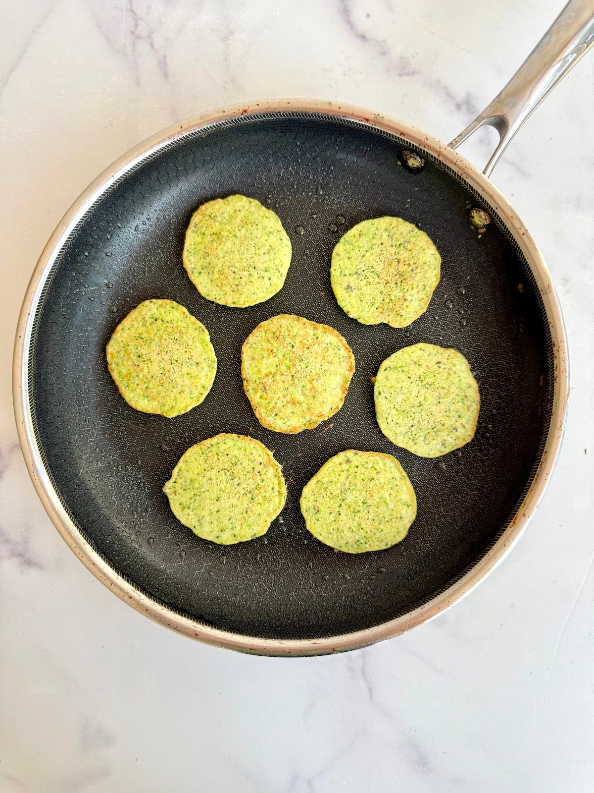 Green veggie pancakes in a skillet.