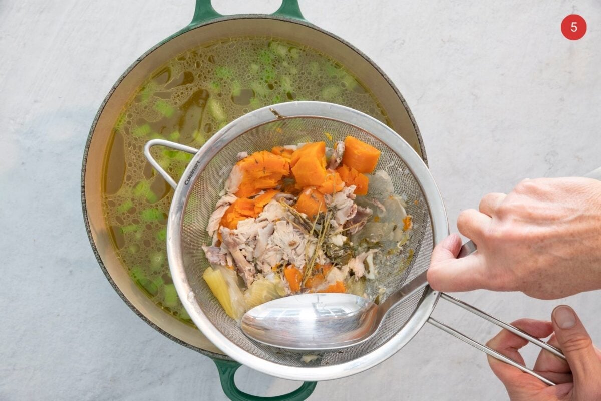 Straining vegetables out of homemade chicken broth.