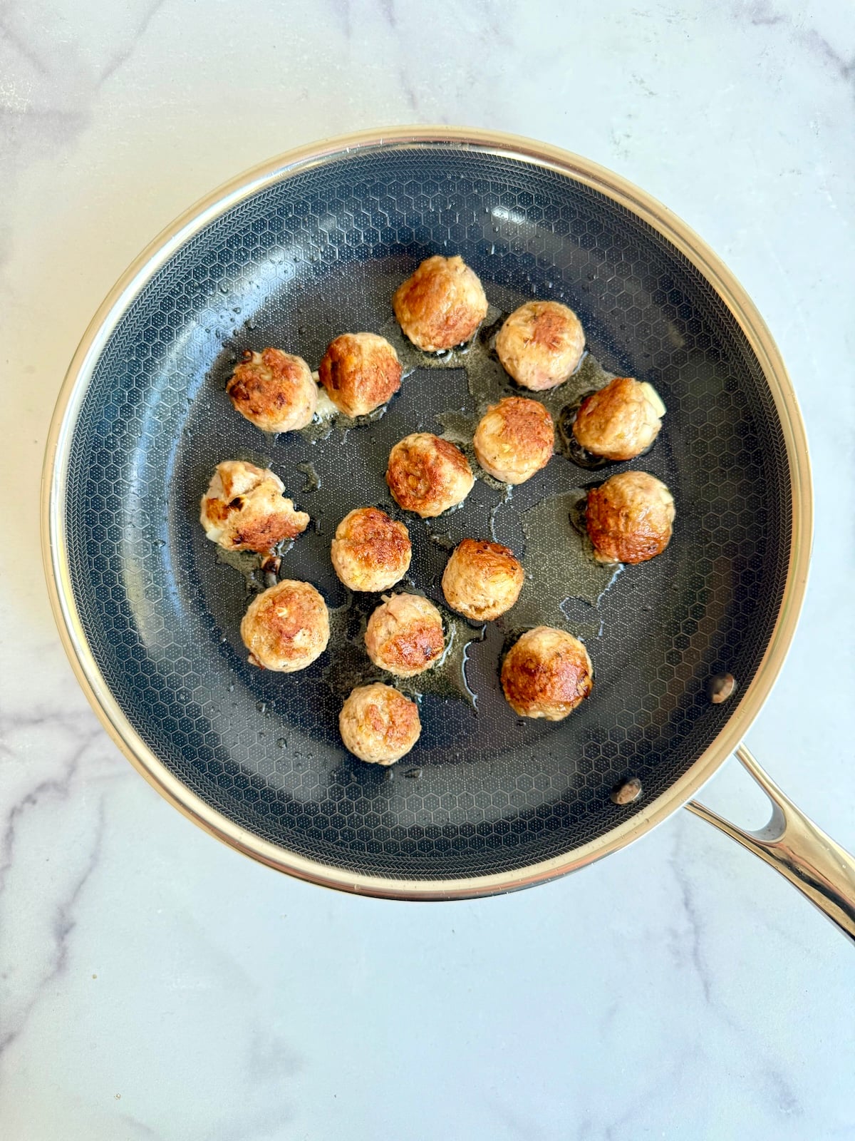 Browned meatballs in a saute pan.