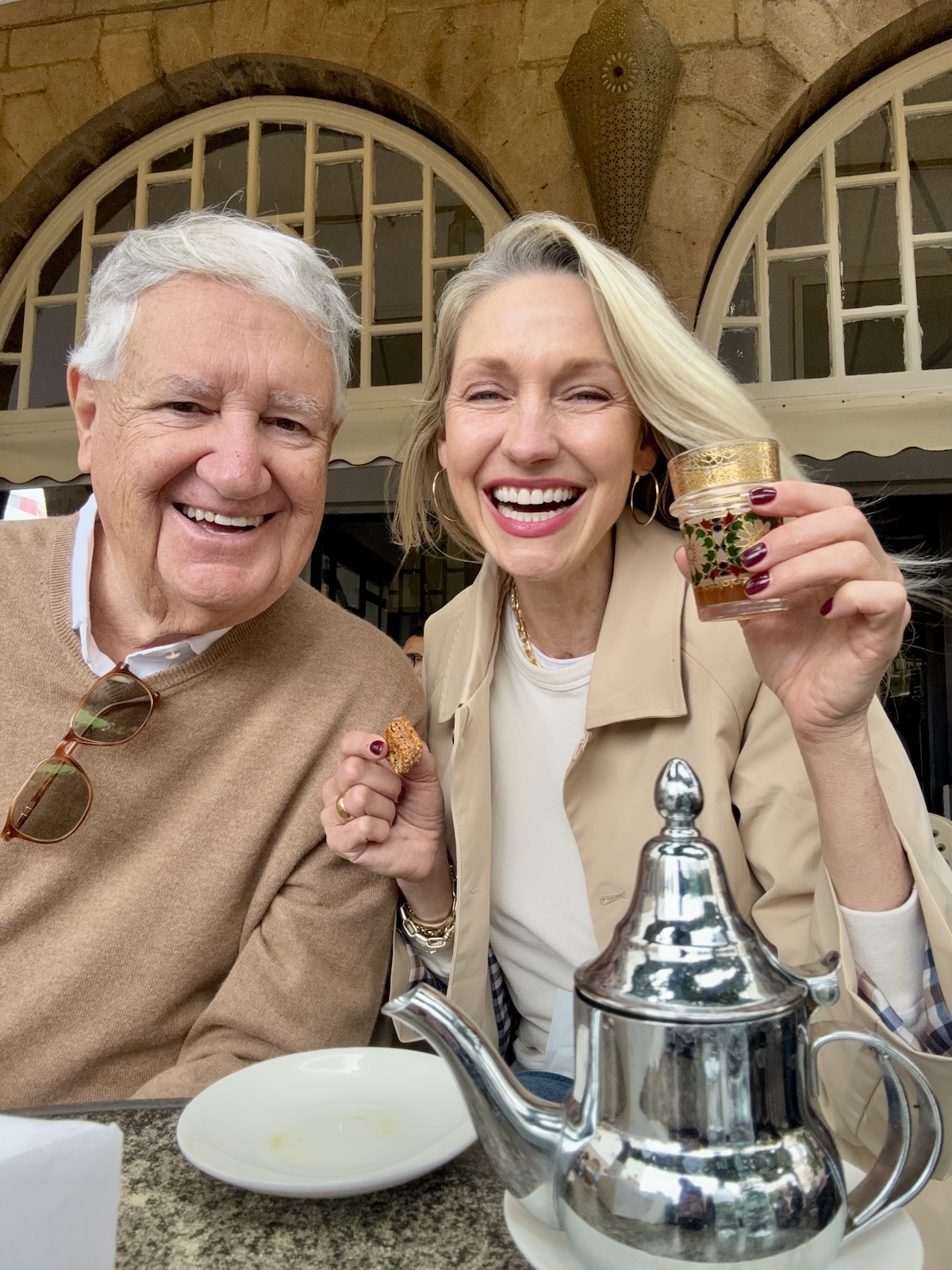 Catherine and her dad laughing together over Moroccan mint tea, silver teapot in the foreground.