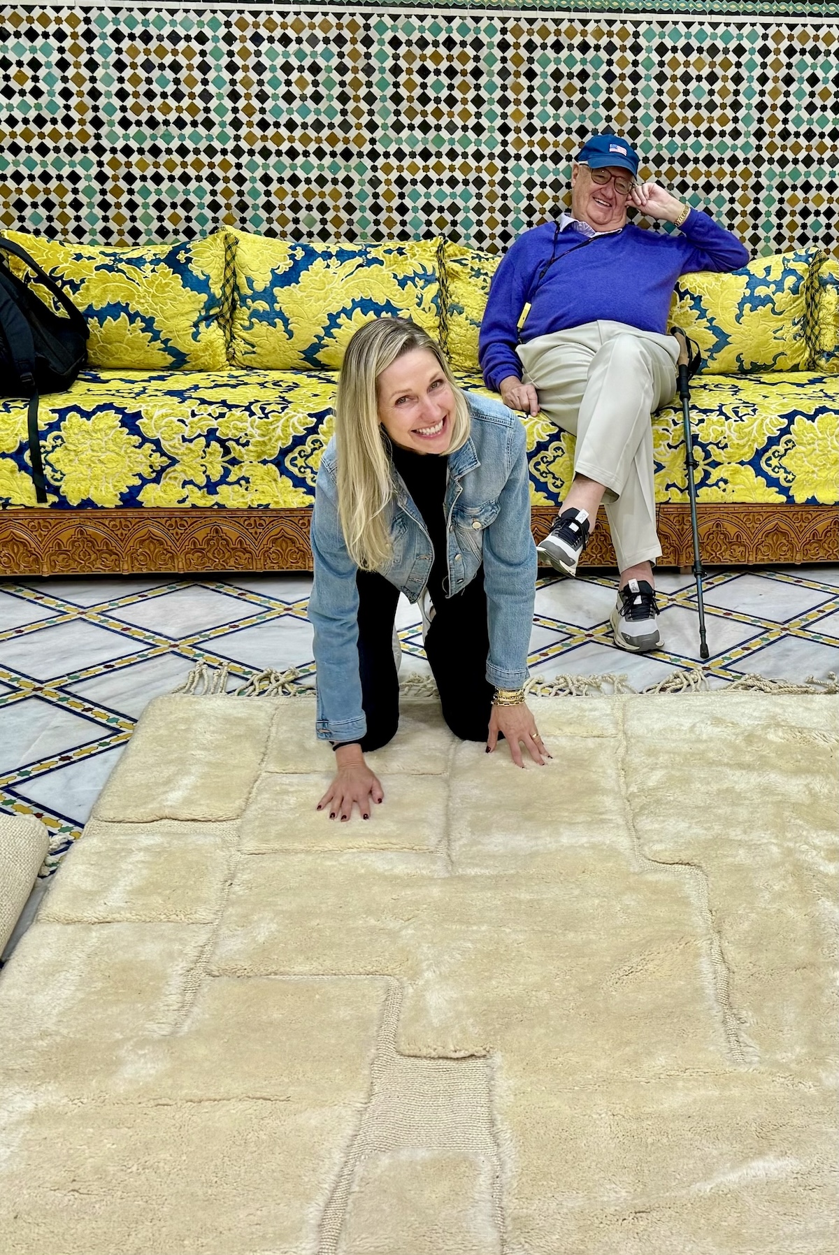 Catherine and her dad inside a beautifully tiled Moroccan riad interior with colorful couch and rug.