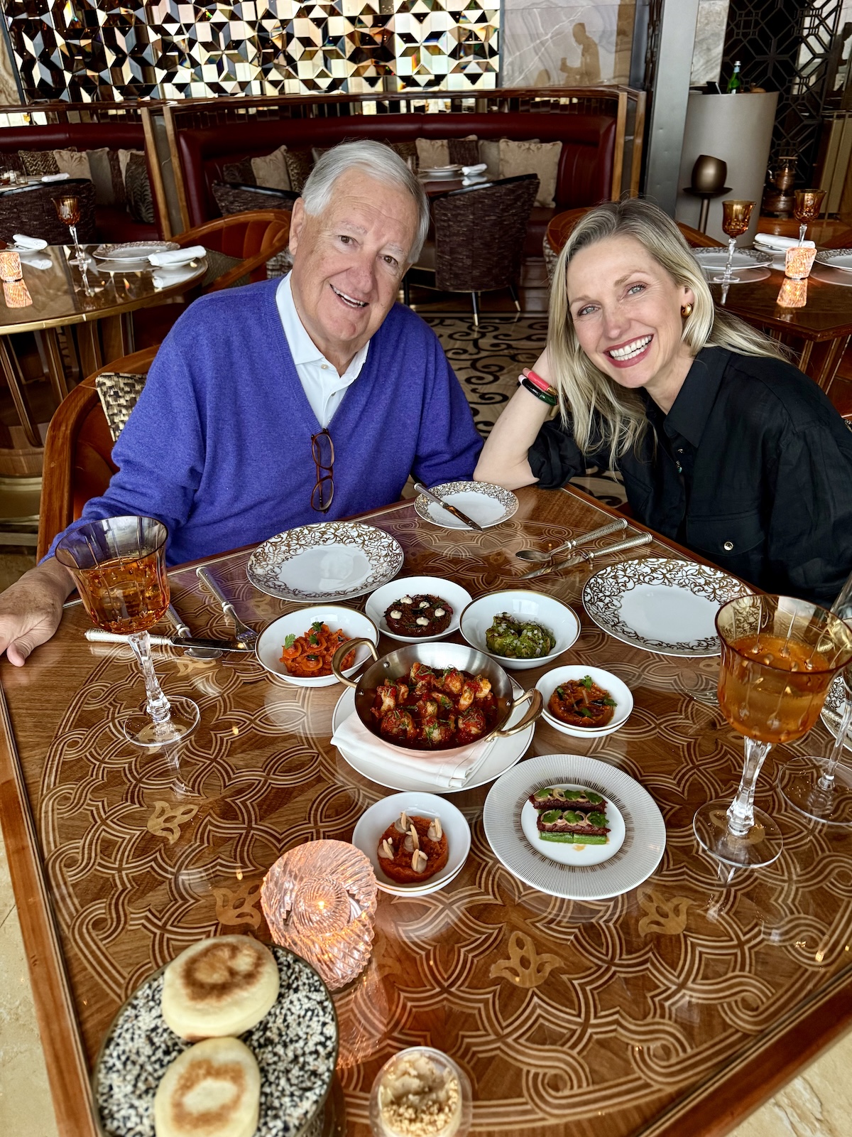 Catherine and her dad at a restaurant table filled with small Moroccan dishes and mezze.