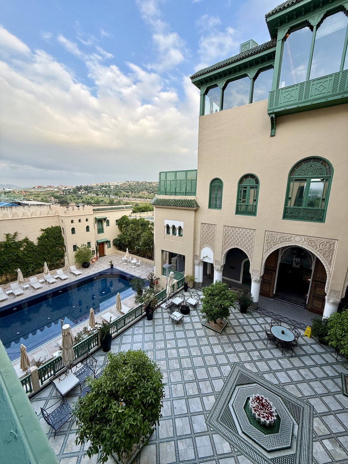 Aerial view of the Palais Faraj hotel courtyard in Fez, showing the pool, ornate arched architecture, and tiled terrace.