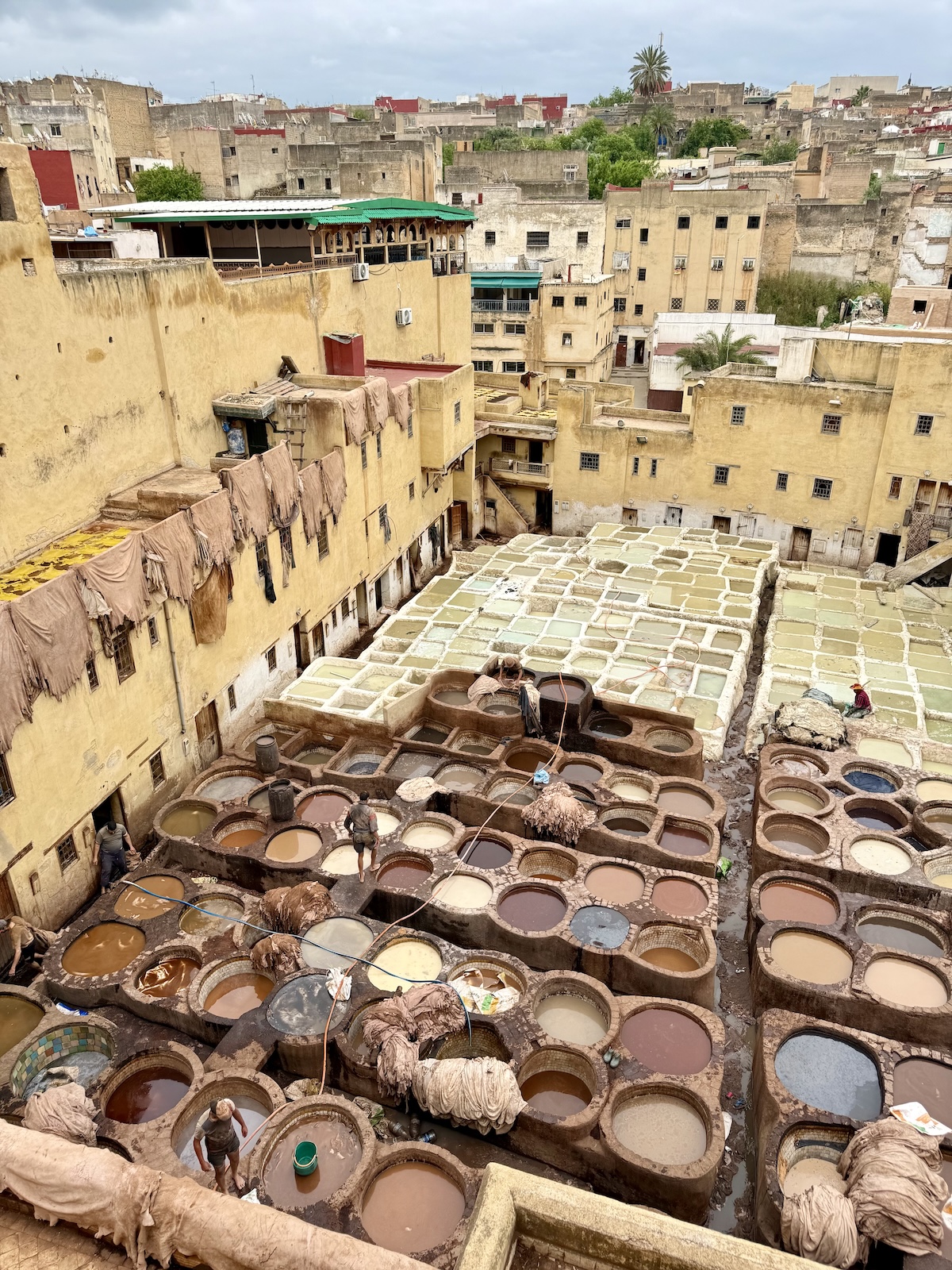 Overhead view of the Fez tanneries, circular stone vats filled with dye in shades of brown, white, and terracotta.