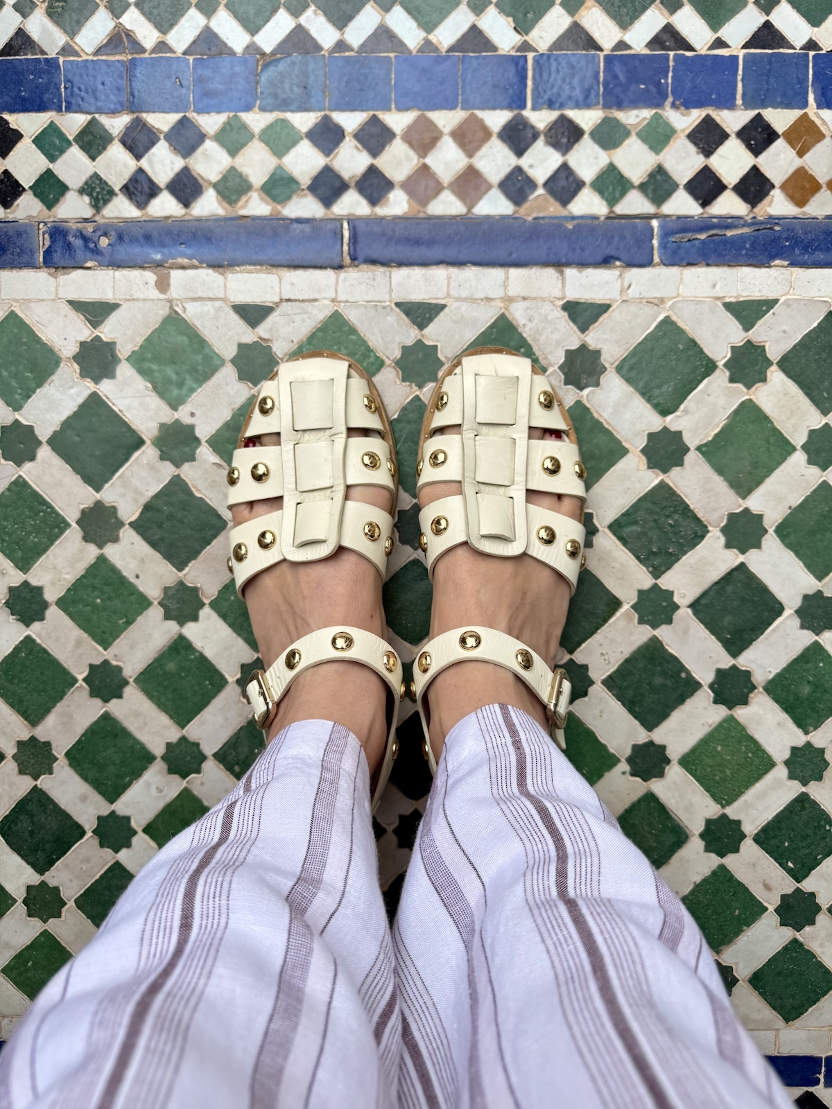 Catherine's sandaled feet on a decorative Moroccan tile floor.