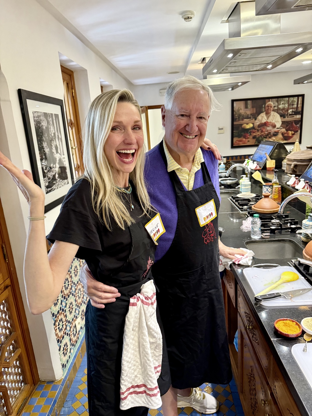 Catherine and her dad posing for the camera at a cooking class wearing aprons.